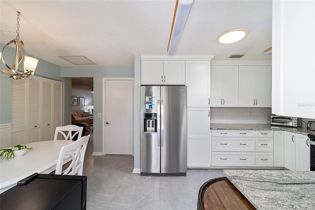 kitchen featuring hanging light fixtures, white cabinetry, stainless steel fridge with ice dispenser, and light stone counters