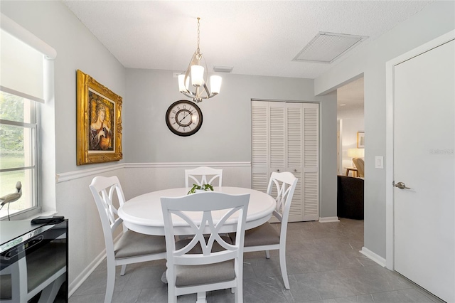 tiled dining room with a chandelier and a textured ceiling