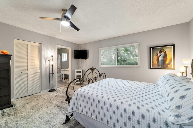 carpeted bedroom with ceiling fan, a textured ceiling, a closet, and ensuite bath