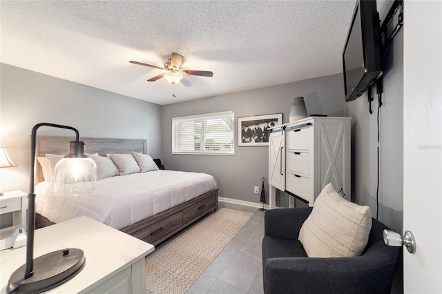 tiled bedroom featuring ceiling fan, a textured ceiling, and a barn door