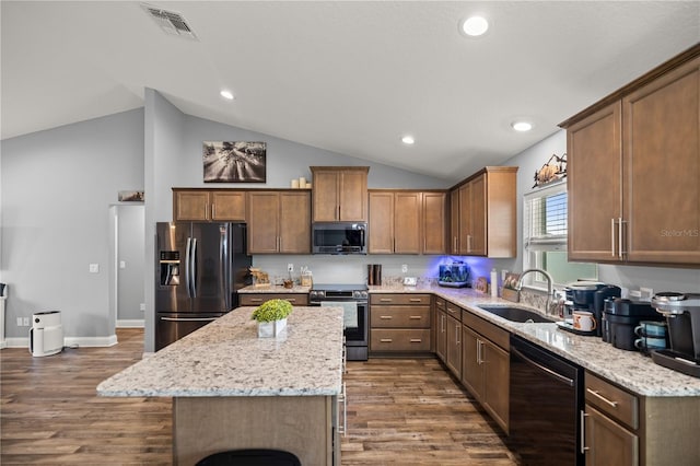 kitchen featuring dark hardwood / wood-style flooring, a center island, appliances with stainless steel finishes, and vaulted ceiling