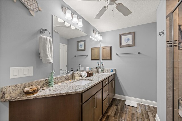 bathroom featuring a textured ceiling, walk in shower, hardwood / wood-style floors, ceiling fan, and vanity