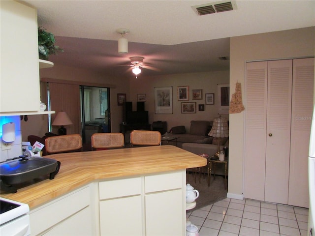 kitchen with wood counters, light tile patterned floors, white cabinetry, and ceiling fan