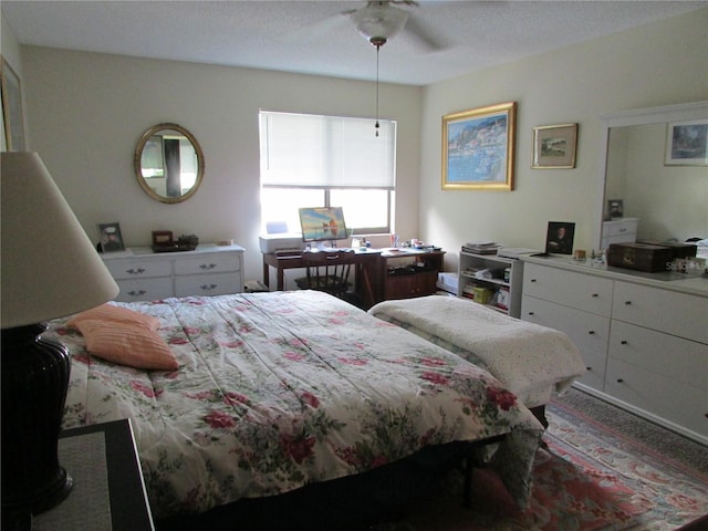 bedroom with ceiling fan, carpet floors, and a textured ceiling