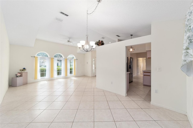 empty room featuring ceiling fan with notable chandelier, lofted ceiling, a textured ceiling, and light tile patterned floors