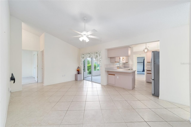 kitchen featuring light tile patterned flooring, stainless steel refrigerator, kitchen peninsula, ceiling fan, and sink