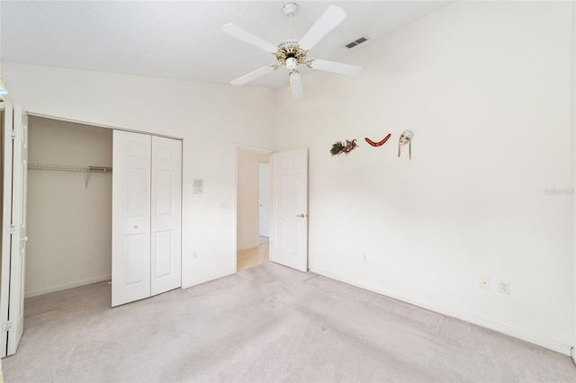 unfurnished bedroom featuring ceiling fan, light colored carpet, a closet, and high vaulted ceiling