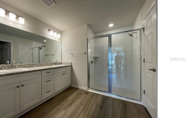 full bath featuring double vanity, visible vents, a sink, and wood finished floors