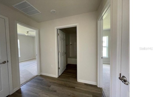 corridor featuring dark wood finished floors, visible vents, and baseboards