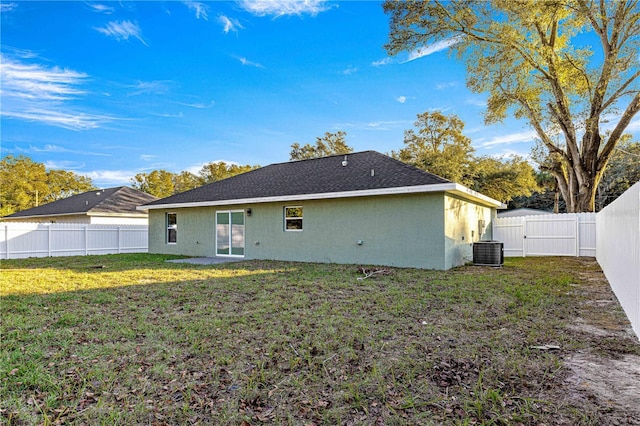 back of house with central AC unit and a lawn