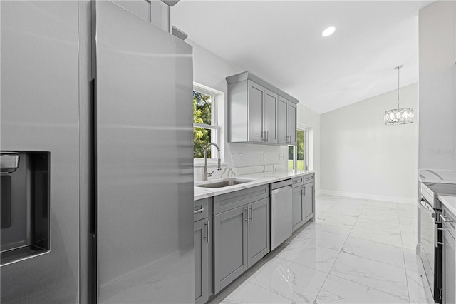 kitchen featuring lofted ceiling, decorative light fixtures, stainless steel appliances, sink, and gray cabinetry