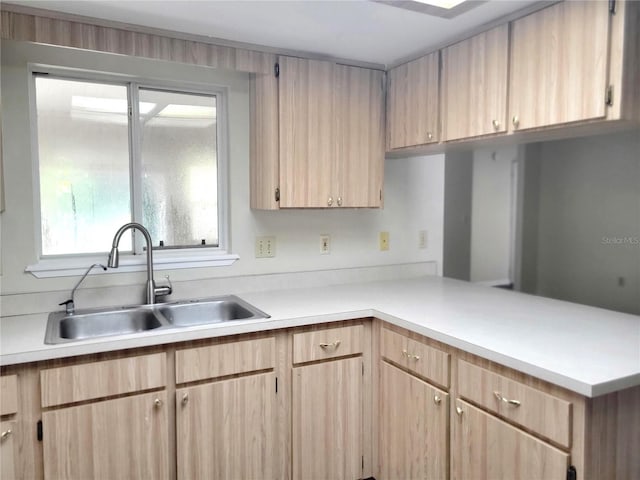 kitchen with kitchen peninsula, light brown cabinets, and sink