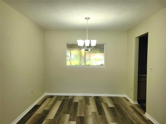 unfurnished dining area with a textured ceiling, dark hardwood / wood-style floors, and a chandelier