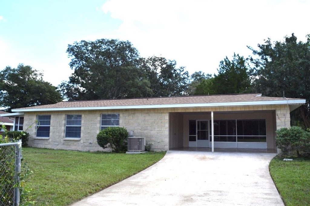 ranch-style home featuring cooling unit and a front lawn