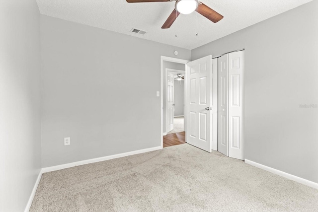 unfurnished bedroom with ceiling fan, carpet floors, a closet, and a textured ceiling