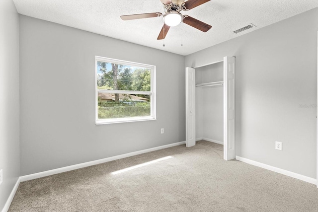 unfurnished bedroom featuring ceiling fan, carpet floors, a closet, and a textured ceiling