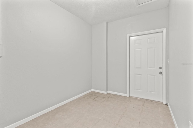 tiled empty room featuring a textured ceiling