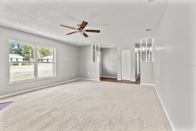 carpeted empty room with ceiling fan and a textured ceiling