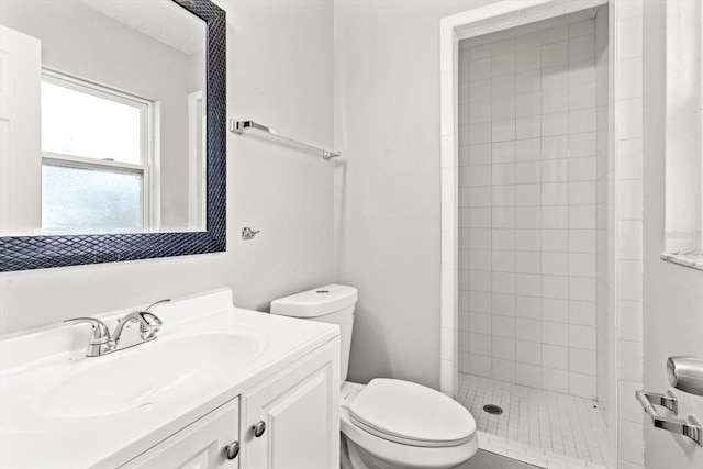 bathroom featuring vanity, toilet, and tiled shower