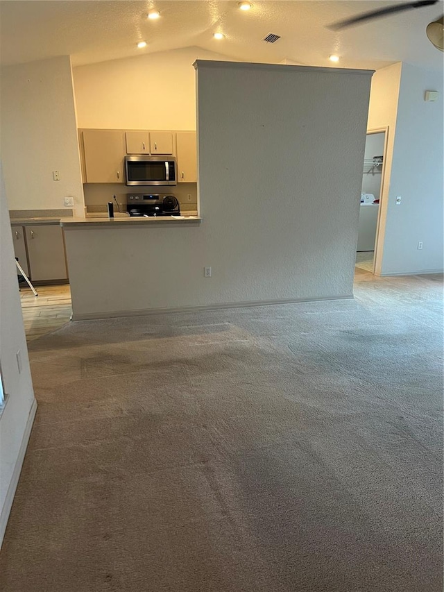 unfurnished living room featuring lofted ceiling, light carpet, and washer / dryer