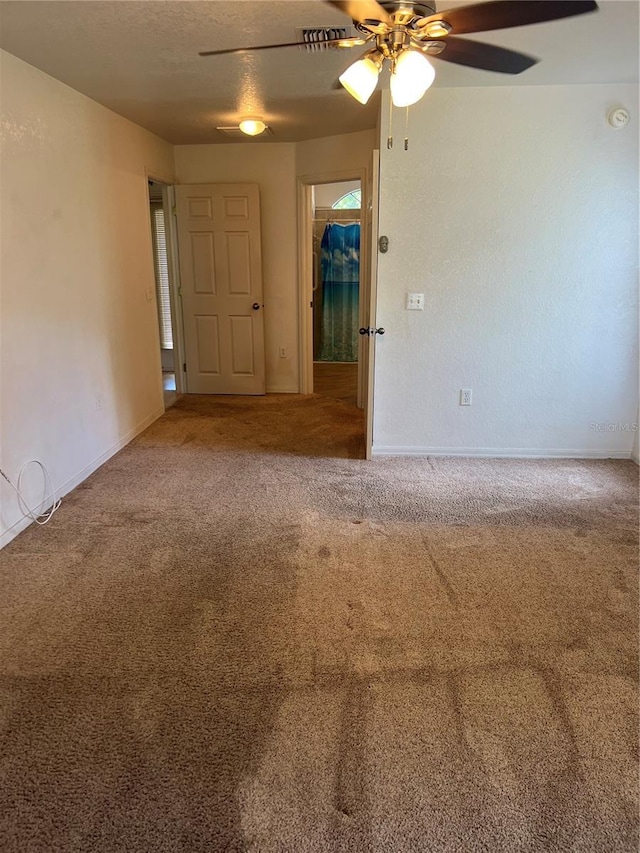 carpeted spare room featuring ceiling fan and a textured ceiling