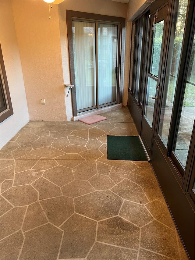 unfurnished sunroom featuring ceiling fan