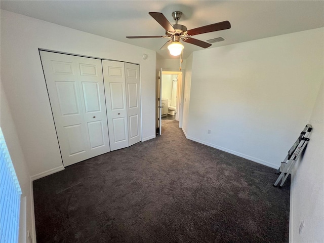 unfurnished bedroom featuring ceiling fan, a closet, and dark colored carpet