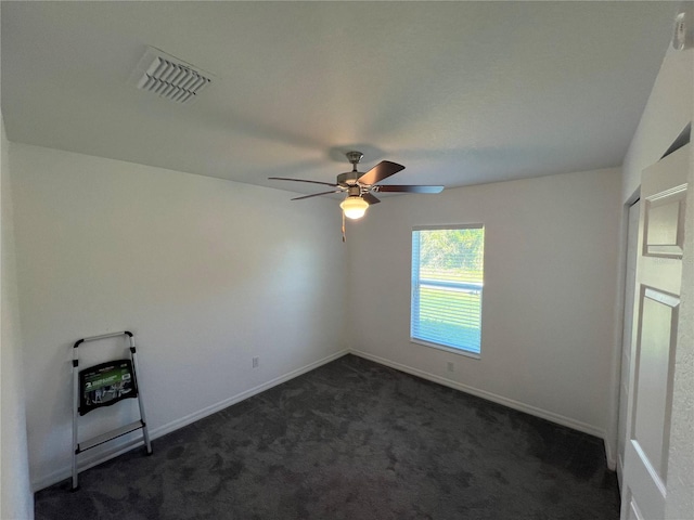 spare room featuring dark colored carpet and ceiling fan