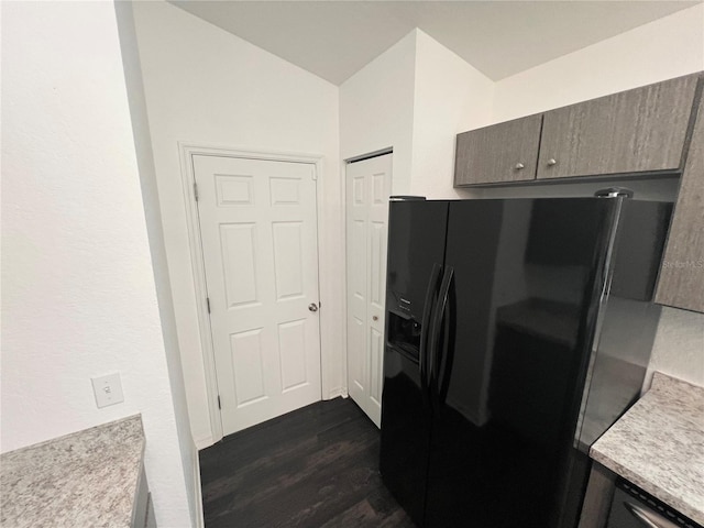 kitchen with vaulted ceiling, dark hardwood / wood-style flooring, and black fridge