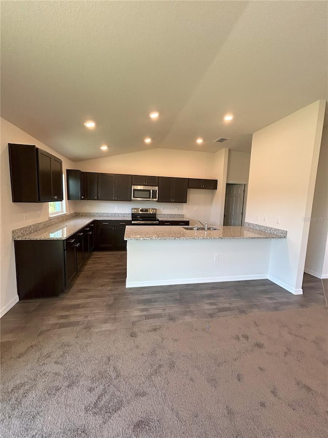 kitchen featuring appliances with stainless steel finishes, lofted ceiling, a sink, and light stone counters