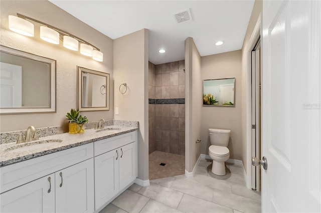 bathroom with a tile shower, tile patterned floors, vanity, and toilet