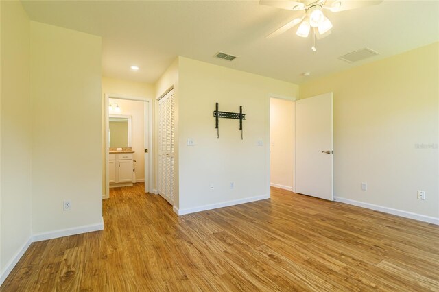 unfurnished bedroom featuring ceiling fan, ensuite bath, and light hardwood / wood-style floors