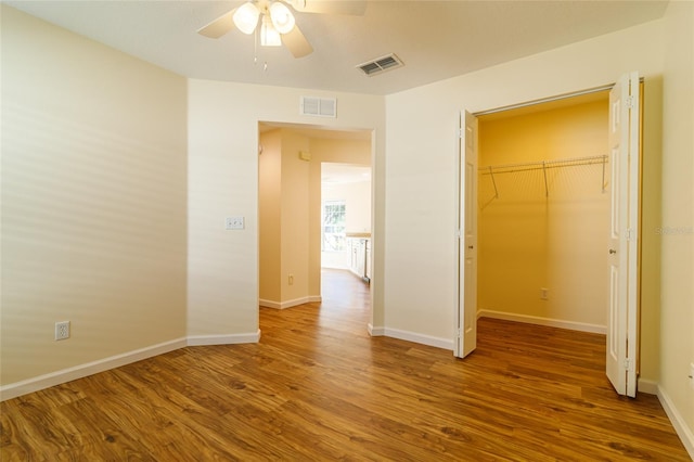 unfurnished bedroom featuring hardwood / wood-style floors, ceiling fan, and a closet