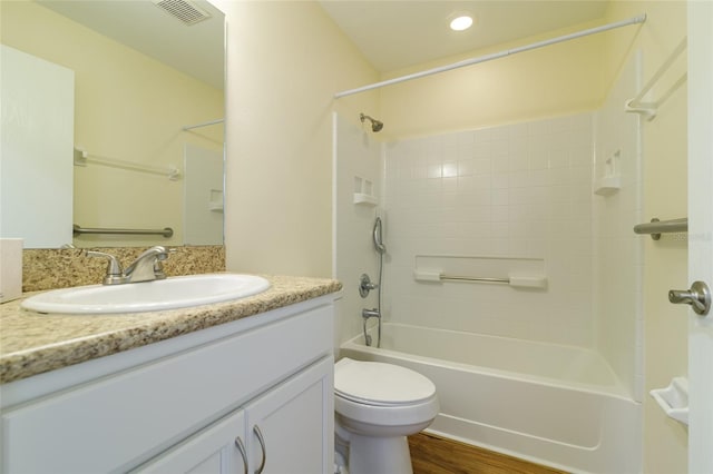 full bathroom featuring tiled shower / bath, vanity, hardwood / wood-style floors, and toilet