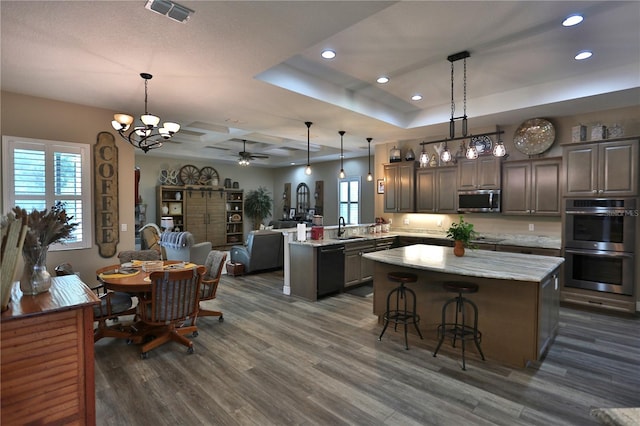 kitchen with appliances with stainless steel finishes, kitchen peninsula, a kitchen island, dark hardwood / wood-style flooring, and sink