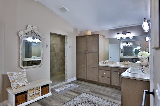 bathroom featuring walk in shower, vanity, lofted ceiling, and wood-type flooring