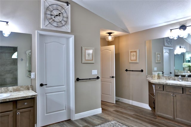 bathroom featuring vanity, hardwood / wood-style floors, and vaulted ceiling