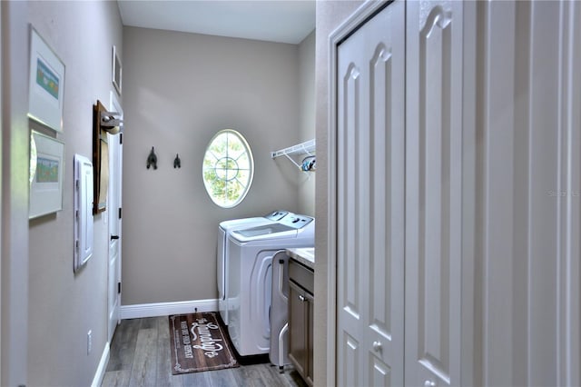 clothes washing area featuring wood-type flooring, separate washer and dryer, and cabinets