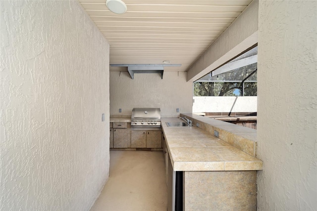 view of patio / terrace with glass enclosure, sink, a grill, and exterior kitchen