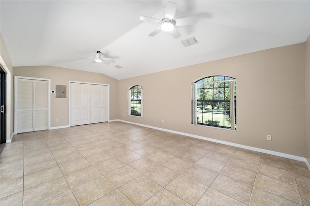 interior space with light tile patterned floors, two closets, ceiling fan, vaulted ceiling, and electric panel