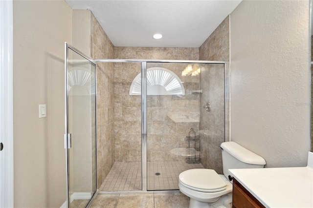 bathroom featuring toilet, tile patterned floors, a shower with door, and vanity