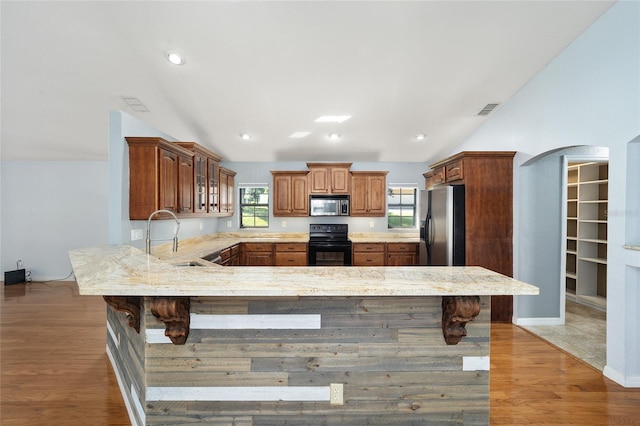 kitchen featuring appliances with stainless steel finishes, lofted ceiling, a breakfast bar, and sink