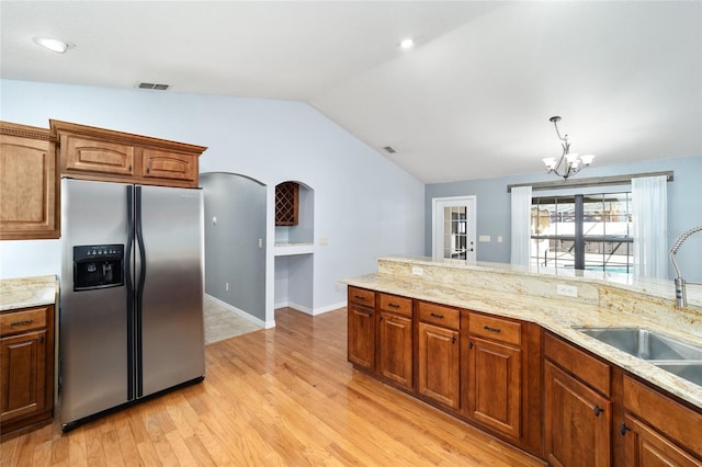 kitchen featuring stainless steel refrigerator with ice dispenser, light wood-type flooring, vaulted ceiling, a chandelier, and sink