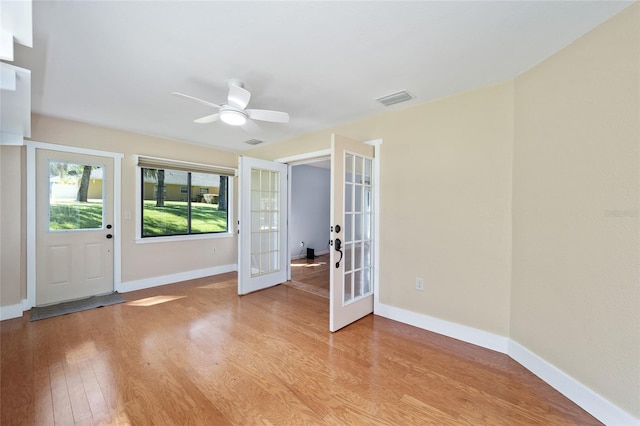 empty room with ceiling fan, french doors, and light wood-type flooring