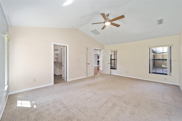 unfurnished bedroom featuring a spacious closet, ceiling fan, a closet, lofted ceiling, and light colored carpet