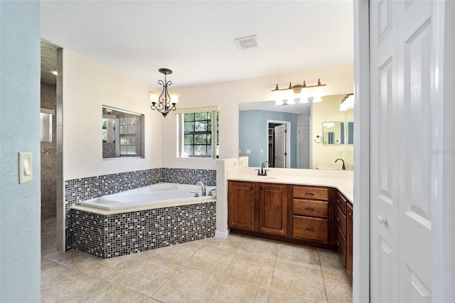 bathroom featuring tiled bath, vanity, tile patterned flooring, and an inviting chandelier