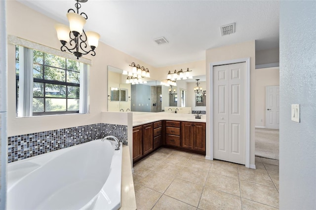 bathroom with a bath, tile patterned floors, vanity, and a notable chandelier