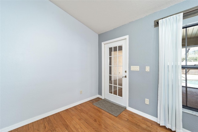 doorway to outside with wood-type flooring and vaulted ceiling