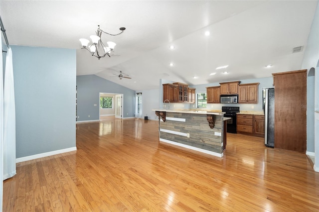 kitchen featuring light hardwood / wood-style floors, plenty of natural light, electric range, a breakfast bar, and a center island