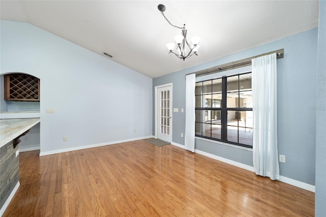 unfurnished dining area featuring lofted ceiling, wood-type flooring, and a chandelier